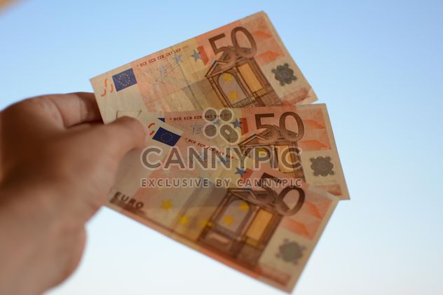 Euro banknotes in hand on blue background - бесплатный image #348421