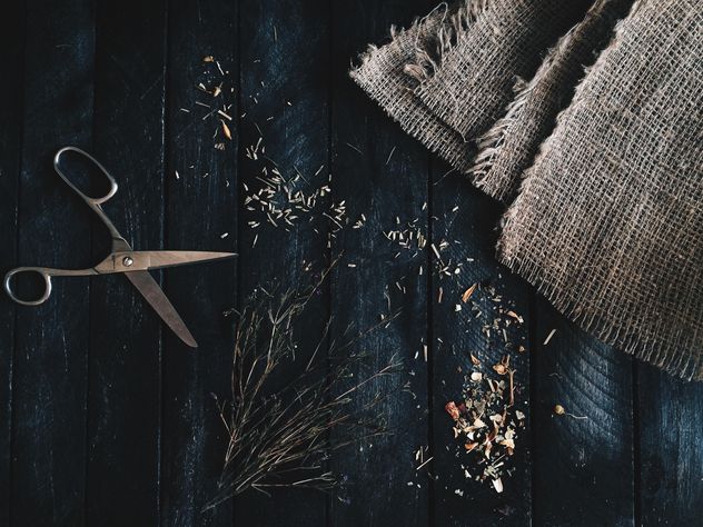 Scissors, burlap and dry herbs on dark wooden background - Free image #136341