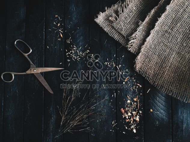 Scissors, burlap and dry herbs on dark wooden background - Free image #136341