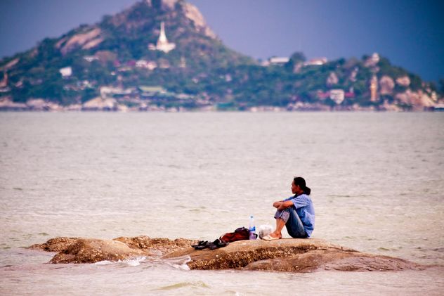 Lonely man sitting on rocks - image #185641 gratis