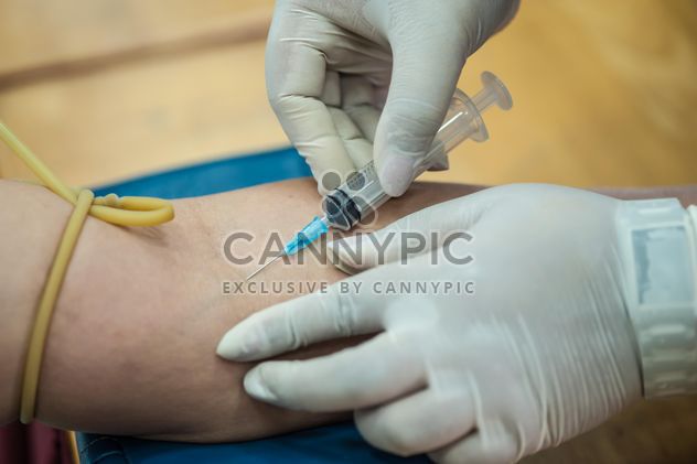 Doctor drawing blood from patient with syringe - image #186341 gratis