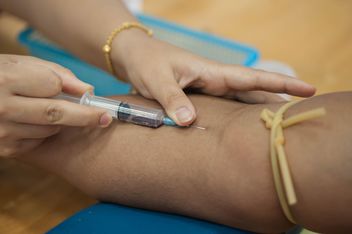 Doctor drawing blood from patient with syringe - image #186581 gratis
