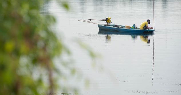 Fisherman in fishing boat on river - image #347281 gratis