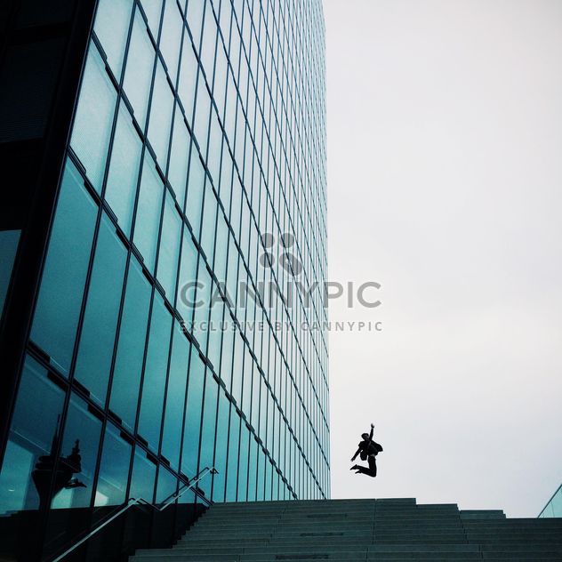 Man jumping by Modern building exterior with glass and metallic facade - Free image #439121