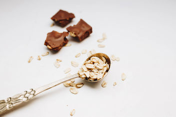 Oat flakes in a vintage spoon and chocolate pieces in the background. White background. - бесплатный image #456011